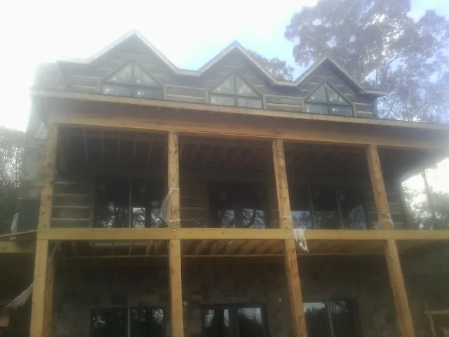 Dormers and porch framing on a large log home under construction — Roof Coating work by our crew in Seward