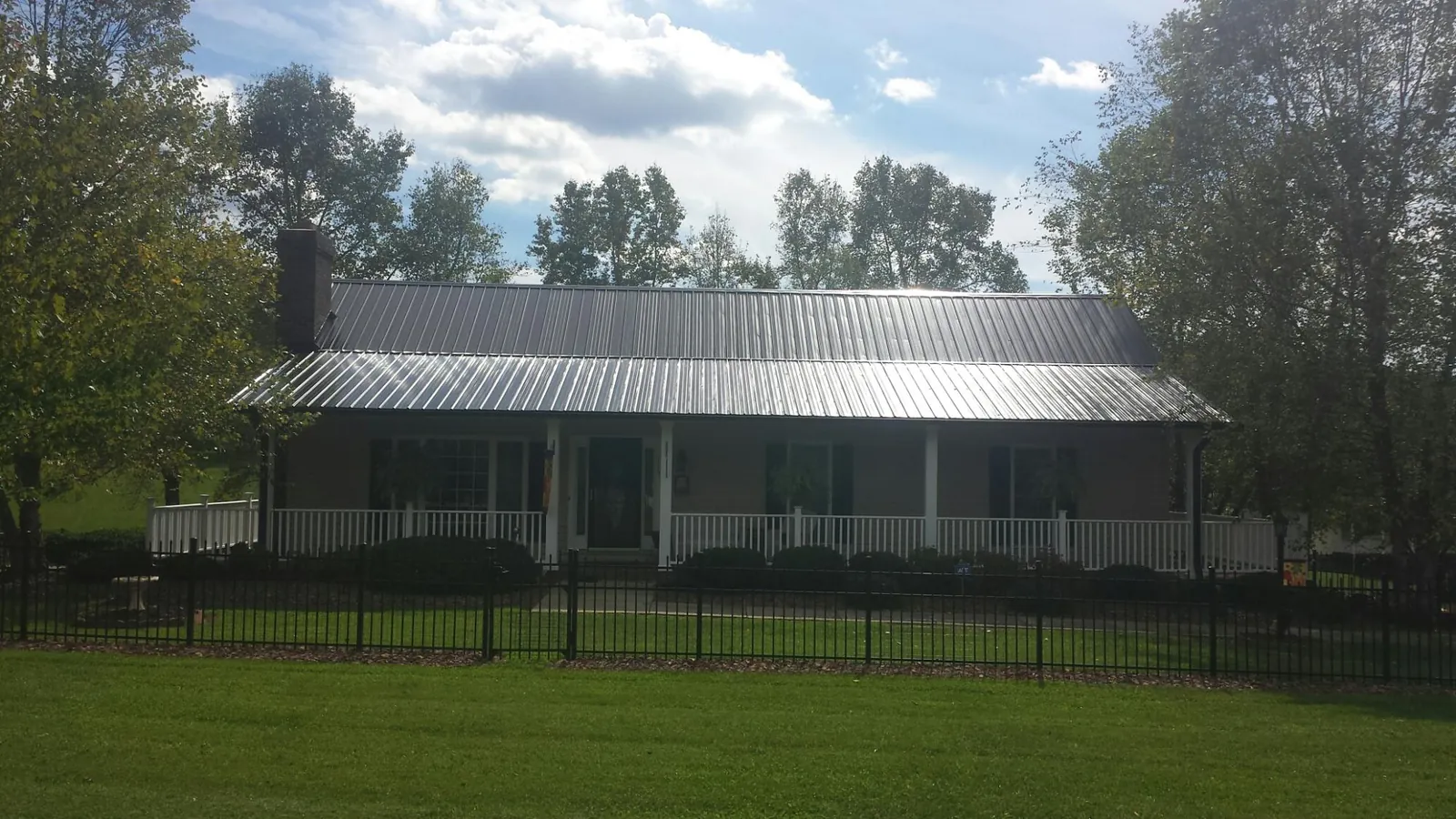 Gray metal roof on a brick ranch with a full width front porch — Gutter Guard Installation work by our crew in Seward