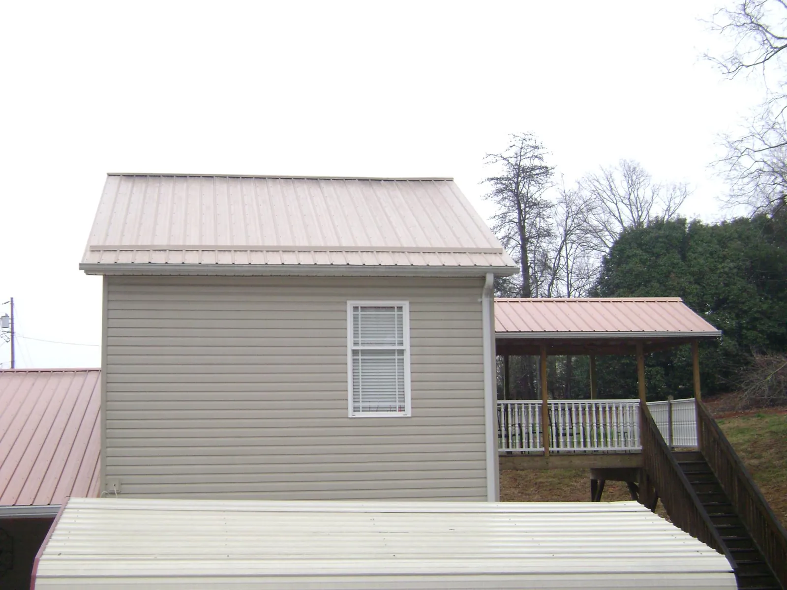 Tan metal roofs on a two story addition and attached porch, from a Roof Replacement job in Seward