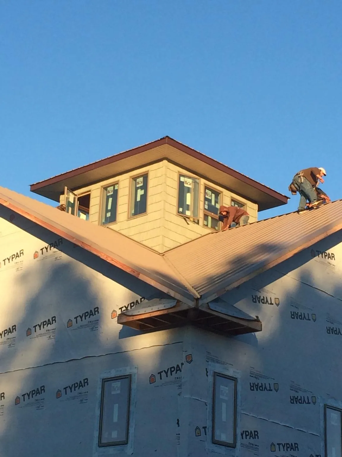 Roofers working around a rooftop cupola on a new metal roof at sunset — Roof Waterproofing in Seward by Roofing Brothers